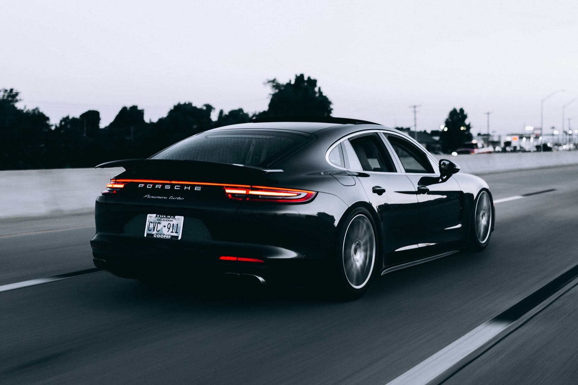 A dark Porsche travelling on an open road
